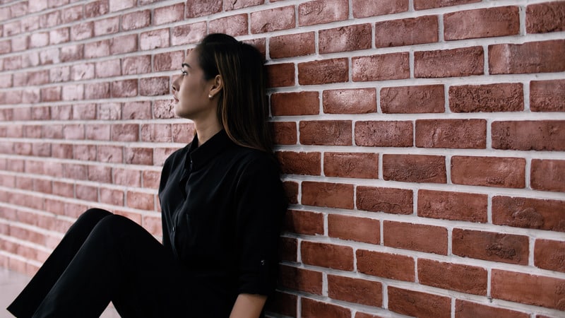 Depressed woman sitting against the wall