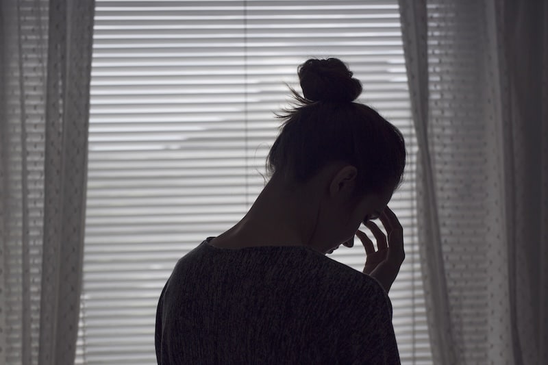 Pensive young woman standing by window