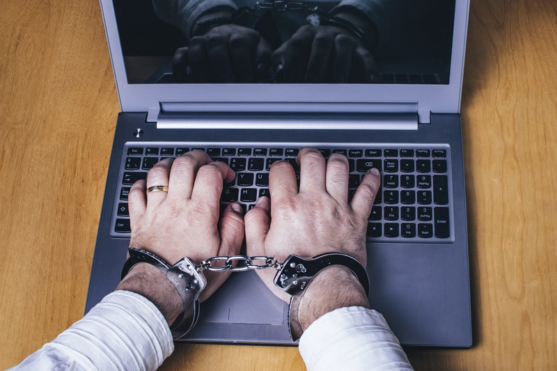 Man hands handcuffed on laptop