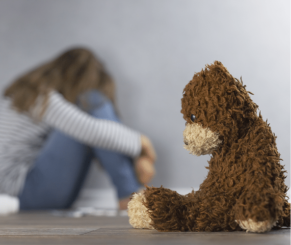 Child sitting with teddy bear scared