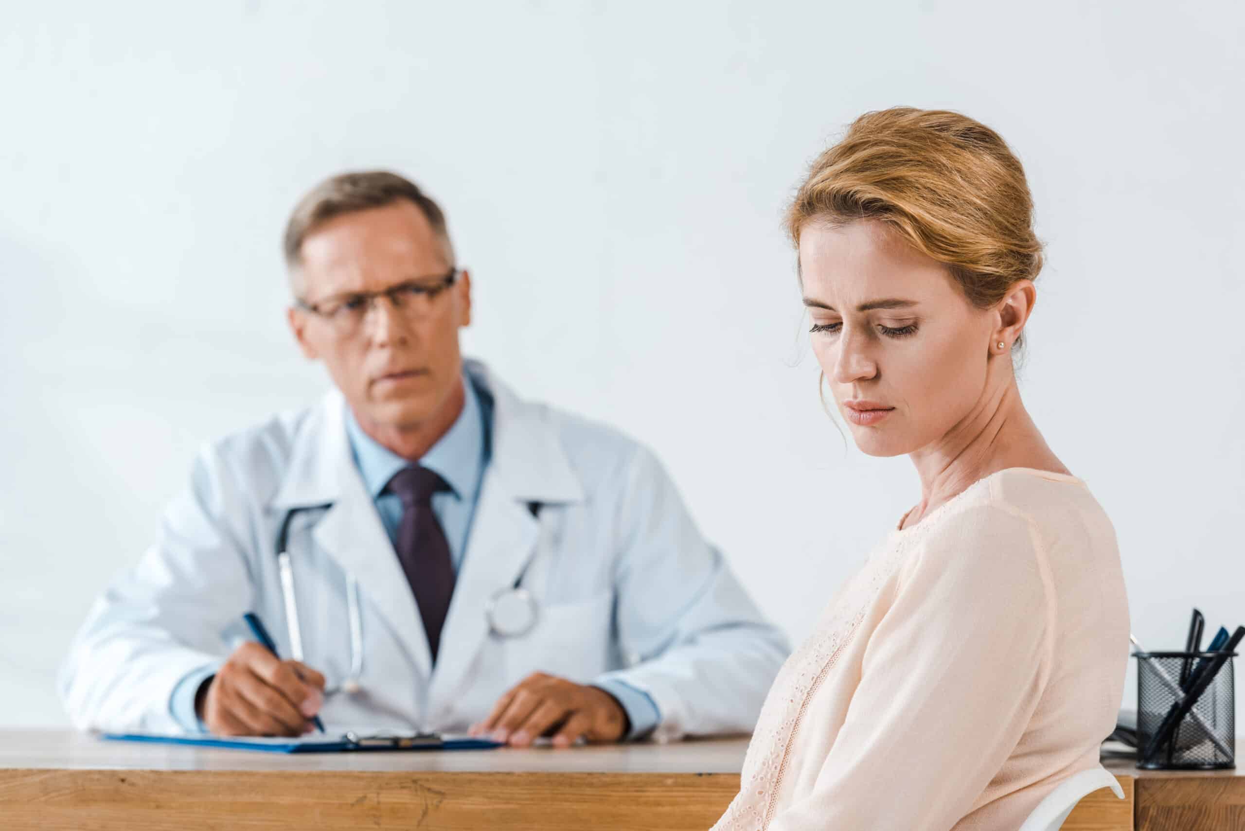 a sad woman sitting near doctor in white coat